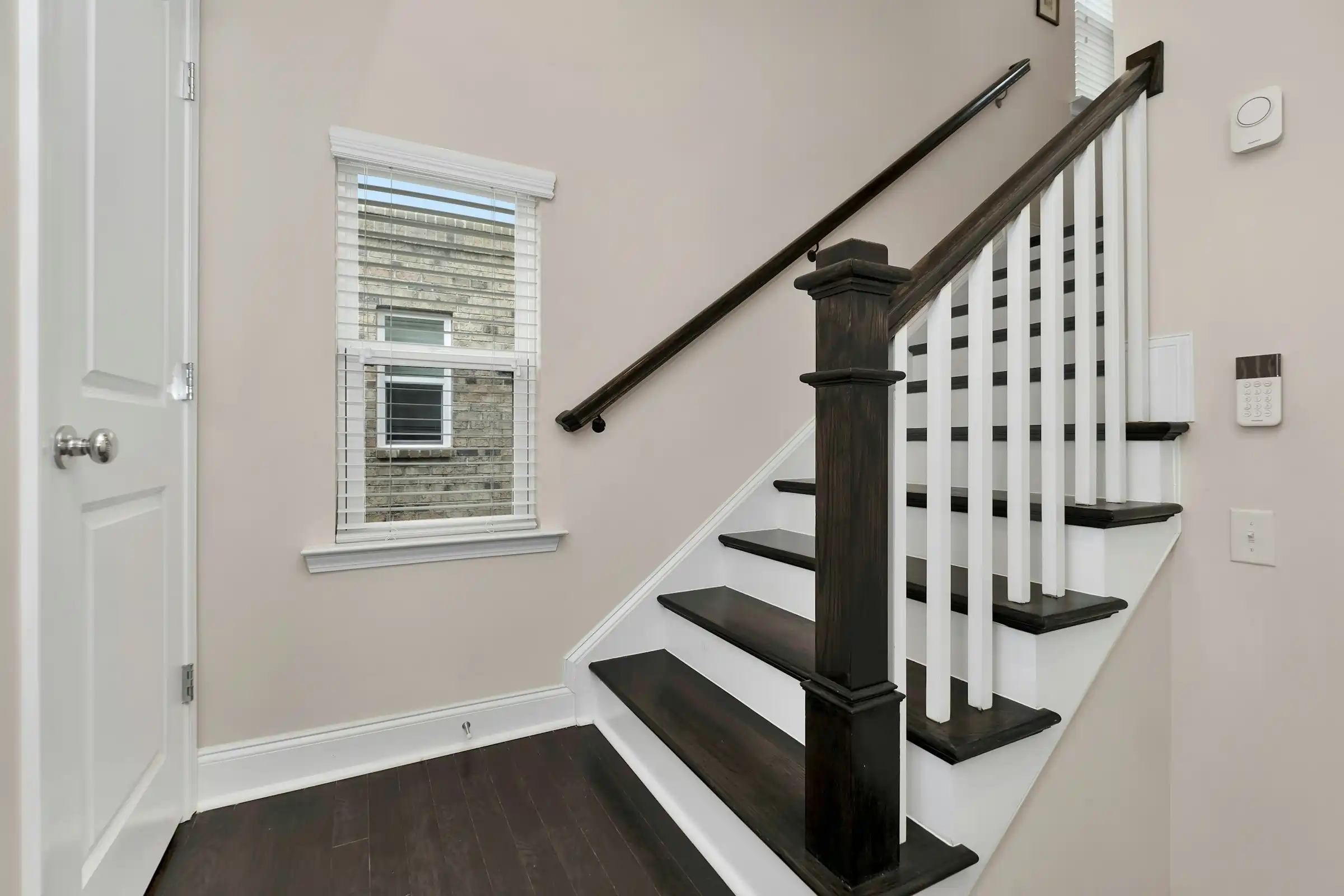 Stair rail installation with dark main rail, white balusters, and black wall rails