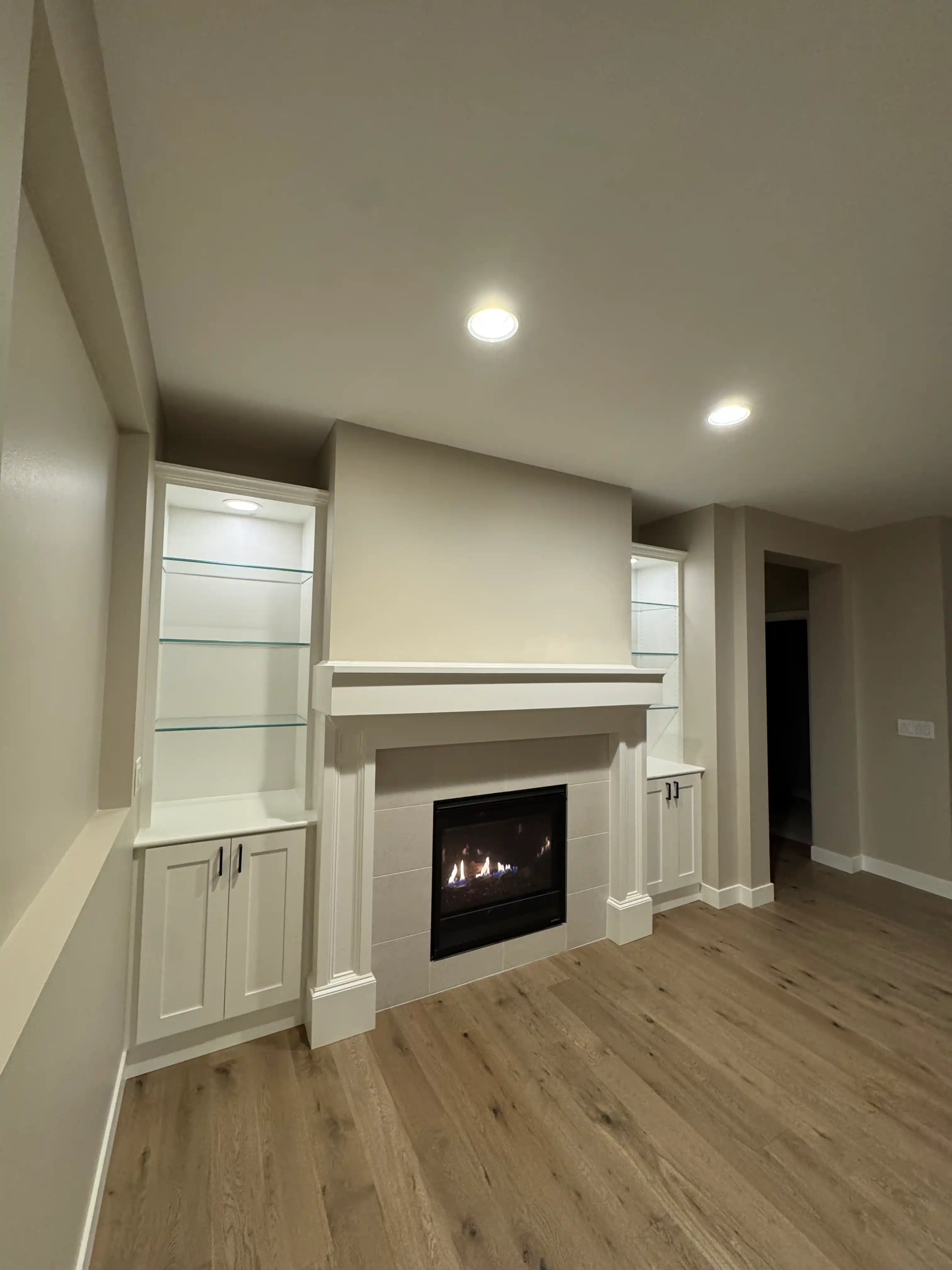 Living room fireplace remodel with glass shelving and white trim surround